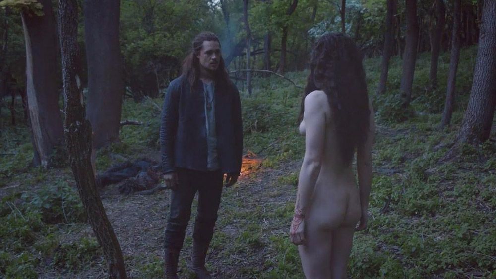 Sexy Charlie Murphy nude is standing in the woods with a guy. 